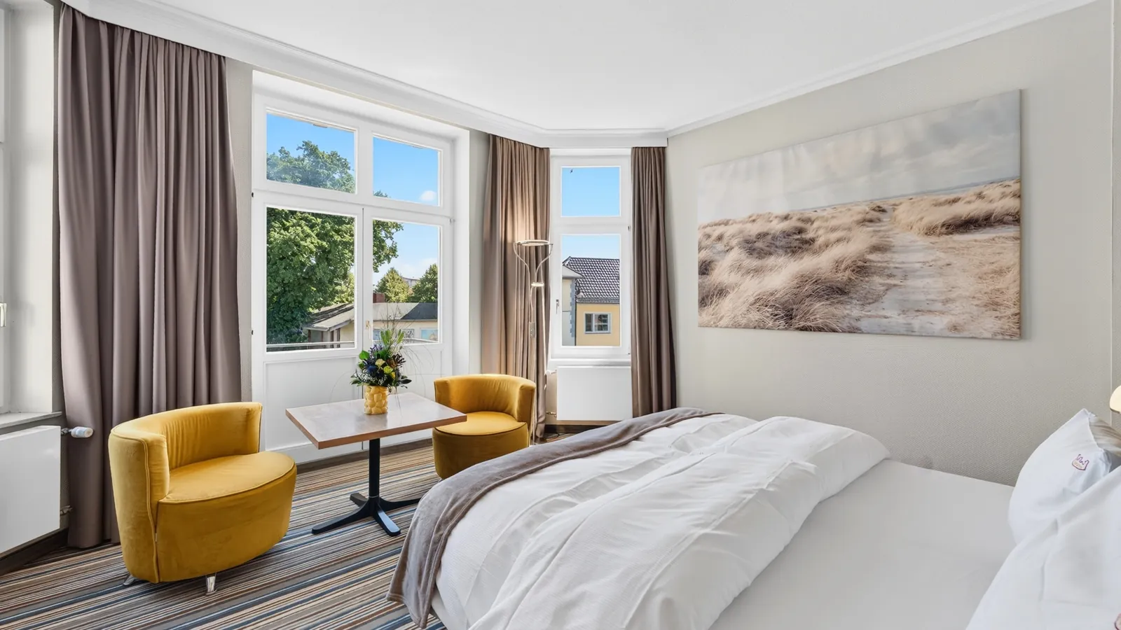 Hotelzimmer mit zwei hellen Fenstern und Sitzecke