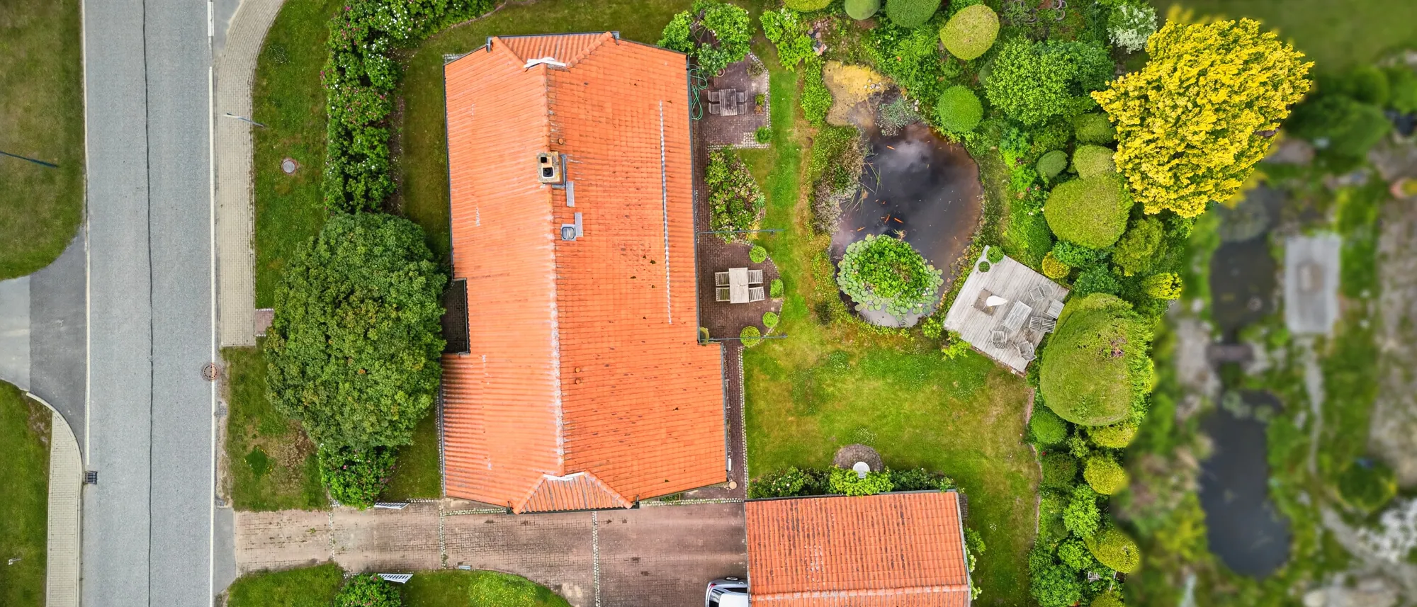 Senkrechte Drohnenaufnahme eines Grundstücks mit Garten und Teich